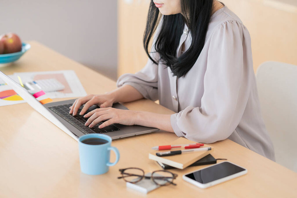 Asiatique femme aux cheveux noirs travaillant à la maison à l'aide d'un ordinateur portable - Photo, image