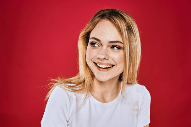 mooie vrouw glimlach wit t-shirt bijgesneden takken rood achtergrond - Foto, afbeelding