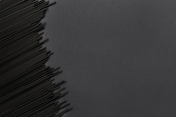 Raw black spaghetti pasta on black background. Food background. Free space for text. - Zdjęcie, obraz