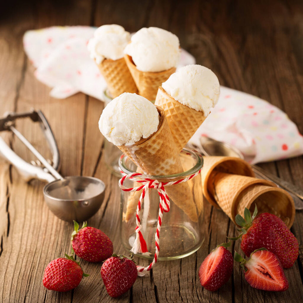 Домашнє ванільне морозиво у вафельних конусах зі свіжою полуницею на сільському дерев'яному фоні. Вибірковий фокус. Смачна концепція літньої їжі
. - Фото, зображення