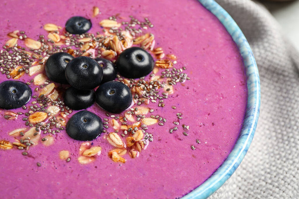 Delicious acai smoothie with granola and chia seeds in dessert bowl on table, closeup - Photo, Image