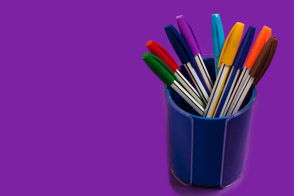 colored pens in a purple penholder - Fotó, kép