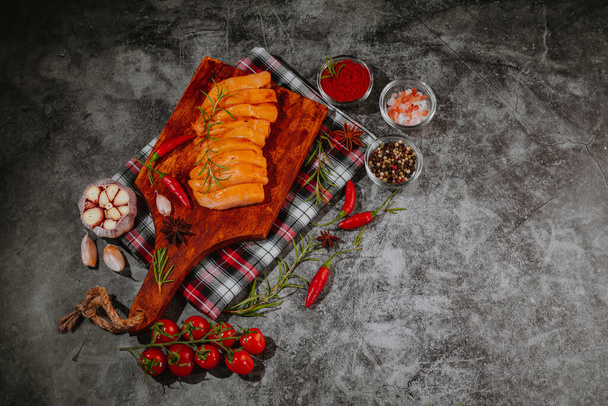 Thinly sliced chicken fillet, breast with cooking spices, chili and rosemary cherry tomatoes, garlic. Chicken meat with vegetables on a gray background.Raw meat.Diet food. Low calories. - Photo, Image