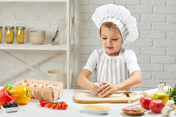 little child boy in cap and an apron cook - Foto, afbeelding