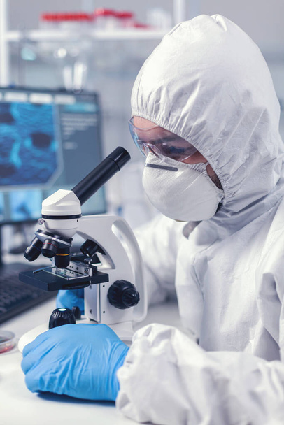 Молодой ученый смотрит в микроскоп, проводя исследования в научной лаборатории - Фото, изображение