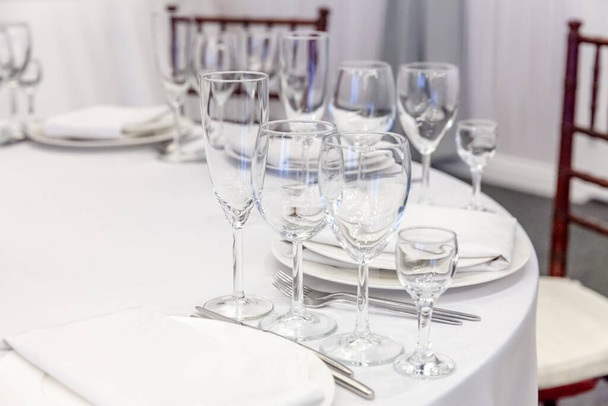 Fancy table set for dinner with napkin glasses in restaurant, luxury interior background. Wedding elegant banquet decoration and items for food arranged by catering service on white tablecloth table - Photo, Image