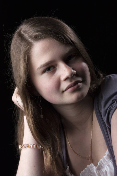 Portrait of young girl with long brown hair on black background - Photo, Image