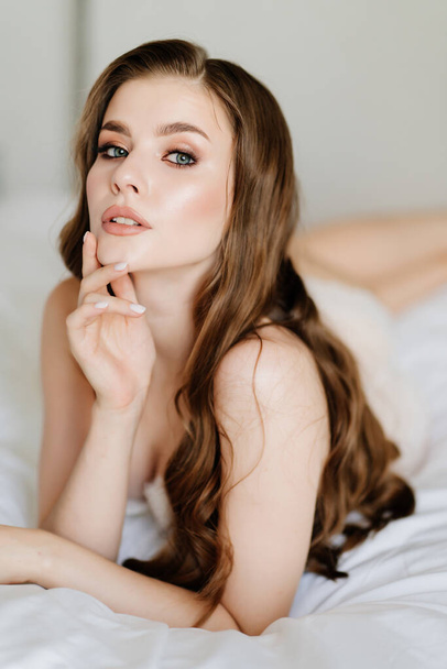 close up. portrait of beautiful woman with long hair in underwear lying on bed. - Foto, imagen