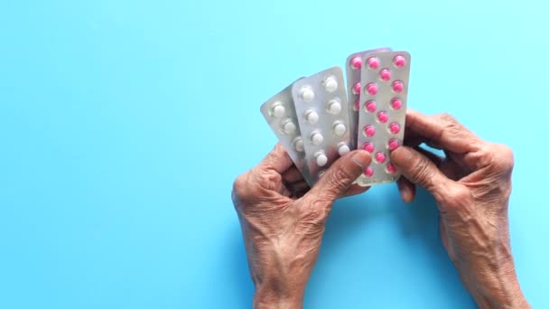  donne anziane in possesso della mano blister pack su sfondo blu  - Filmati, video