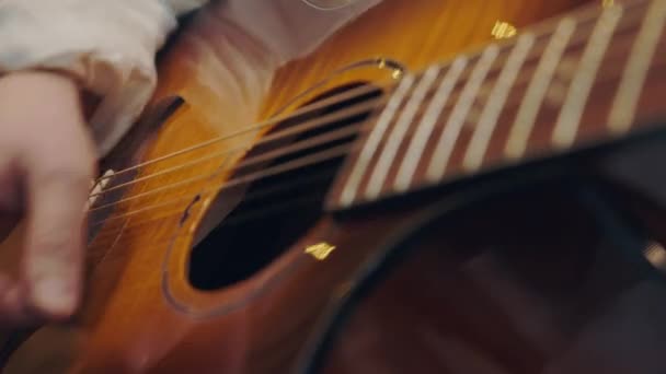 Una mano masculina toca la guitarra de cerca en cálida luz y tonos cálidos. Tocando guitarra acústica. - Imágenes, Vídeo