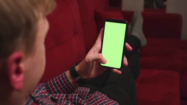 Voltar vista close-up mãos homem segurando chromakey tela verde smartphone assistir conteúdo, jogar jogo, deslizando rolagem no sofá em casa. Gadgets conceito de pessoas. - Filmagem, Vídeo