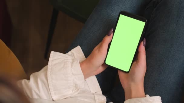 Feche as mãos da mulher segurando o smartphone de tela verde chromakey assistindo conteúdo, deslizando rolagem, escreve no telefone em casa ou no escritório. Gadgets conceito de pessoas. - Filmagem, Vídeo