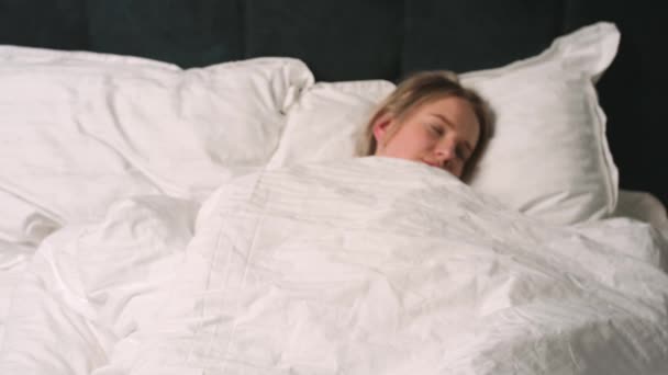 Vista frontal de la joven mujer bonita sorprendida durmiendo y levantándose rápido mientras está acostado en la cama.  - Metraje, vídeo