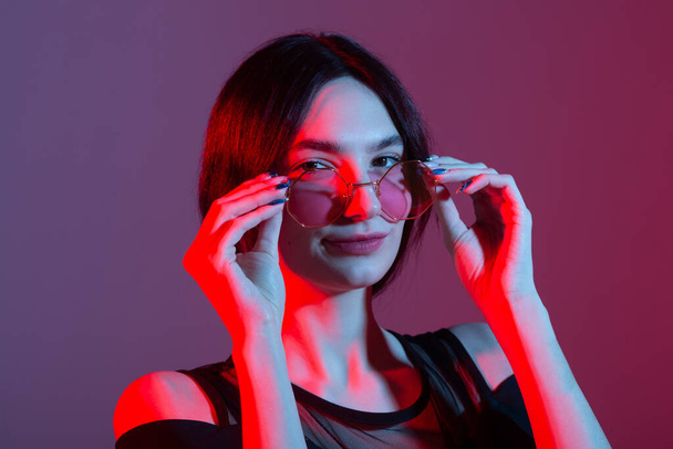 portrait of a beautiful young woman with colored lighting in sunglasses - Valokuva, kuva
