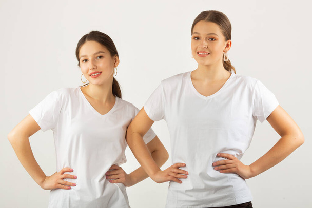 twee mooie jonge vrouwen in witte t-shirts op een witte achtergrond - Foto, afbeelding