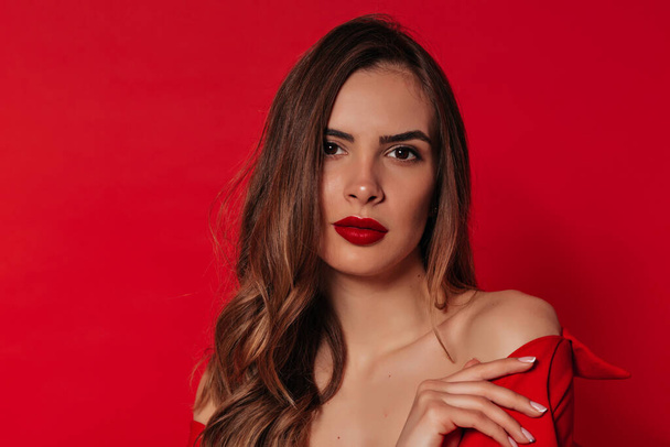 Close up beautiful woman with light-brown hair and red lips posing over red background in Valentine's day. High quality photo - Foto, Imagem
