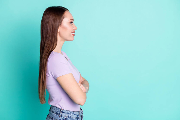 Side profile photo of girl with crossed hands looking at empty space smiling isolated on vibrant teal color background - Fotó, kép