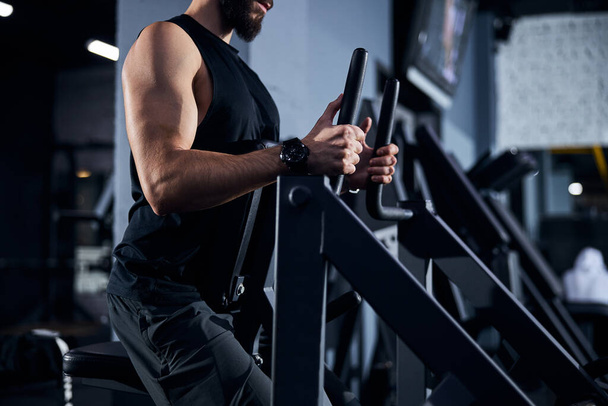 Atleta masculino que move as alças de uma máquina de levantamento de peso - Foto, Imagem