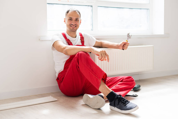 Portret van een vrolijke reparateur met apparatuur in het appartement - Foto, afbeelding
