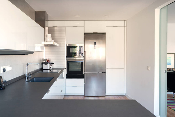 Moderne Küche mit weißen Schränken und schwarzer Arbeitsplatte - Foto, Bild