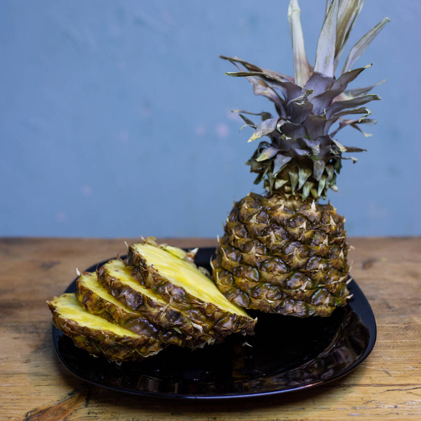Pineapple on a plate. Cut and on a wooden table. - Foto, Imagen