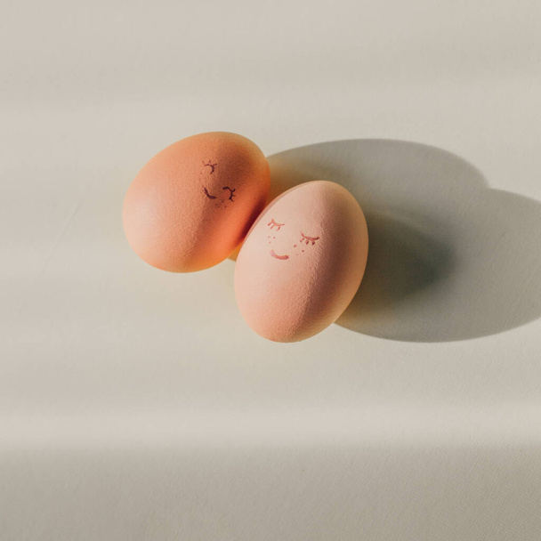 Dvě vařená vejce s roztomilými dekorativními usmívajícími se tvářemi. Pár v konceptu lásky. Valentýnské přání, nebo kreativní kulinářský nápad na velikonoční oslavu.   - Fotografie, Obrázek