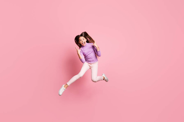 Foto de tamaño completo de niña pequeña emocionada salto hacer v-signo de desgaste suéter púrpura aislado sobre fondo de color pastel - Foto, Imagen
