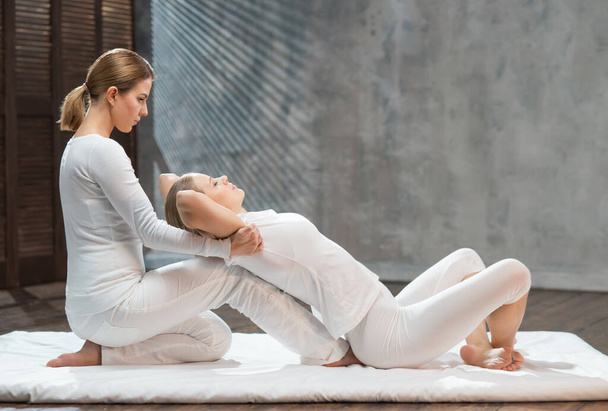 Young woman is getting Thai massage treatment by therapist. Traditional Asian stretching therapy. - Φωτογραφία, εικόνα