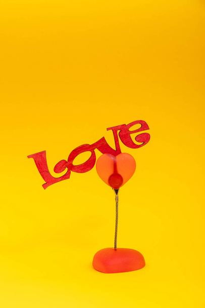 Ξύλινη λέξη Αγάπη σε κίτρινο φόντο. Ημέρα του Αγίου Βαλεντίνου έννοια. - Φωτογραφία, εικόνα