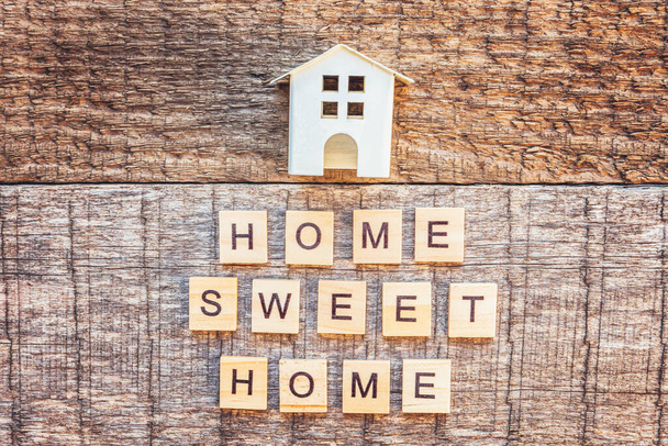 Мініатюрний іграшковий будинок з написом HOME SWEET HOME літери слова на дерев'яному фоні. Страхування іпотечної власності концепція будинку мрії. Плоский простір копіювання верхнього перегляду
 - Фото, зображення