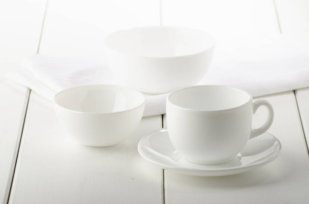white dishes on a white wooden background - Foto, afbeelding