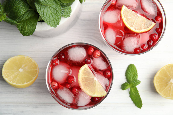 Tasty refreshing cranberry cocktails with lemon on white wooden table, flat lay - Фото, изображение