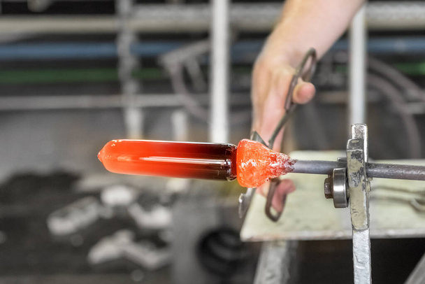 Μετατρέποντας μια ζεστή μάζα γυαλιού που προέρχεται από ένα ζεστό φούρνο σε έργο τέχνης. Η διαδικασία παραγωγής γυαλιού από κοντά. Moser Glass Factory στην Τσεχική - Φωτογραφία, εικόνα