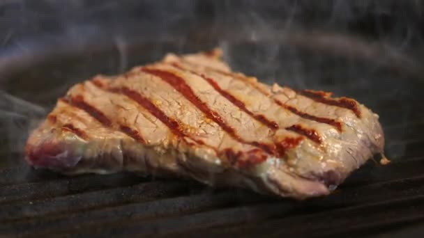 stek wołowy jest smażony na gorącej patelni grillowej - Materiał filmowy, wideo