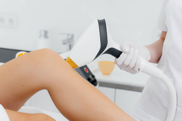 A beautiful young girl will undergo laser hair removal with modern equipment in a Spa salon. Beauty salon. Body care - Φωτογραφία, εικόνα