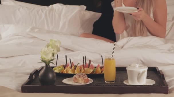 Ρομαντικό πρωινό στο κρεβάτι, κοντά σε ένα δίσκο με φρούτα, χυμό και ένα φλιτζάνι καφέ - Πλάνα, βίντεο