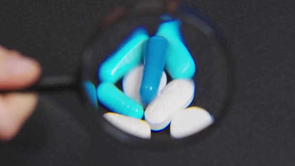 Regardez à travers une pilule d'analgésique de loupe, pilule d'antibiotiques, pilule de gonflement et comprimé de calcium. Pilules analgésiques - concept de pharmacie et de traitement. - Séquence, vidéo