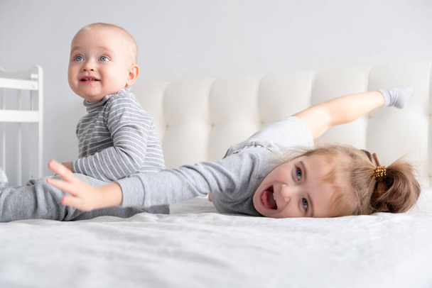 bébé garçon et petite fille soeur s'amuser à la maison sur le lit. Accueil activités pour les enfants. - Photo, image