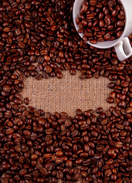Roasted coffee grains background with place for text, cup with coffee grains. - Fotoğraf, Görsel