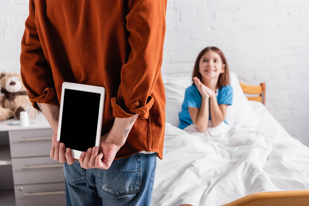 back view of man holding digital tablet with blank screen near excited girl in hospital, blurred background - Valokuva, kuva