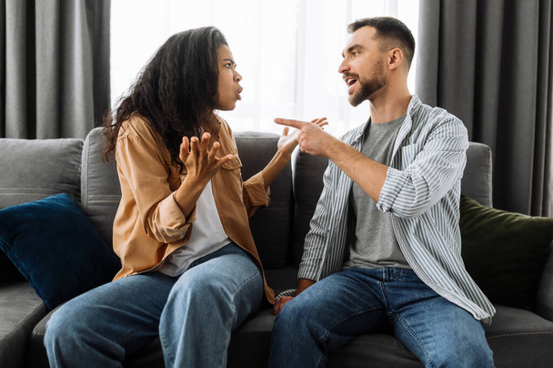Married young couple emotional discuss about something, they having problem. African american woman and caucasian man disagree with each other have a misunderstanding, cant make decision, a quarrel - Photo, Image