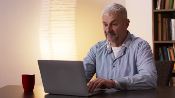 Anciano emocionalmente enraizamiento para su equipo favorito viendo deportes juego en línea en el ordenador portátil en casa, cámara lenta - Metraje, vídeo