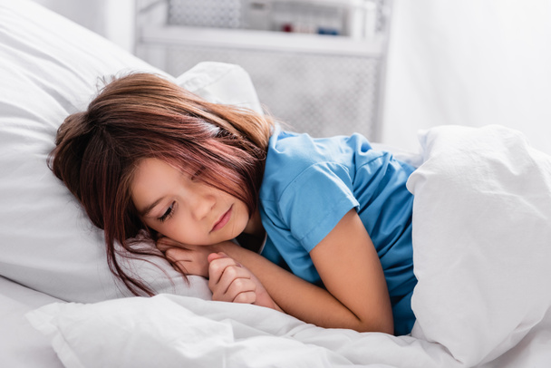 diseased, sad girl lying on bed in hospital - Zdjęcie, obraz