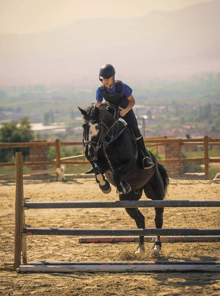 馬術スポーツ,黒馬接近.ジャンプ,前から撮影.高速サラブレッドの馬に乗ってジョッキー  - 写真・画像