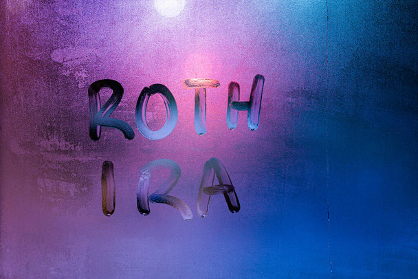 roth iraという単語-個々の退職者のアカウント-夜ぬれた窓ガラス表面に手書き。アイデアはウィリアム・ロス上院議員によって提案された - 写真・画像