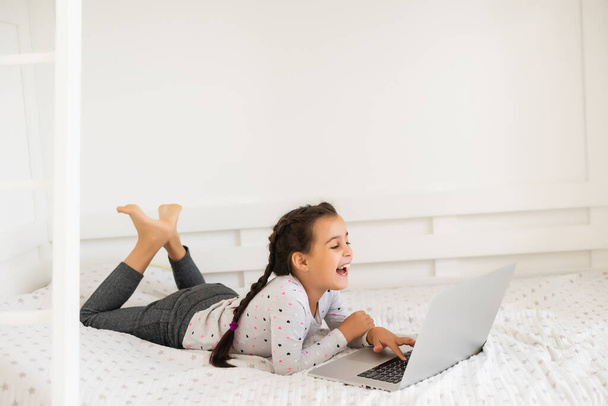 Маленькая девочка учится в Интернете, используя свой ноутбук дома - Фото, изображение