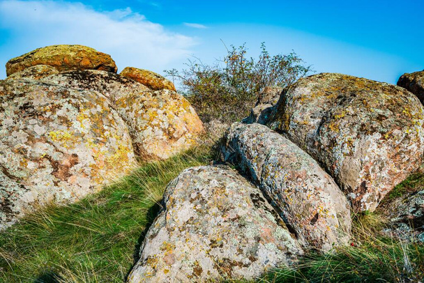 Huge deposits of old stone minerals covered with vegetation in a meadow filled with warm sun in Ukraine and its beautiful nature - Foto, Imagem