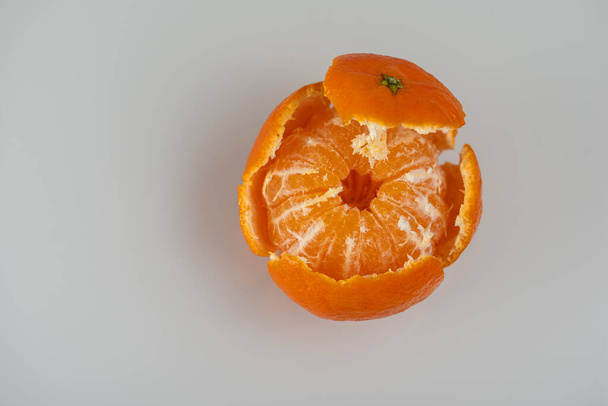 lédús édes mandarin vagy mandarin gyümölcs, amelynek egy része világos alapon hámozott, felülnézetből. Magas kulcs. Van egy hely a feliratnak. Szelektív fókusz  - Fotó, kép