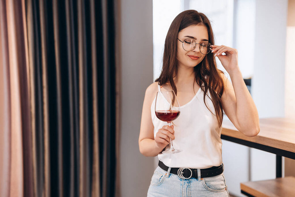 メガネの若い美人さんが自宅で赤ワインを飲んでいます。自由な女性。フリーランスの女性リラックス - 写真・画像