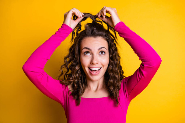 Photo portrait of woman making silly ponytail smiling wearing pink crop-top isolated on bright yellow colored background - Foto, Imagen